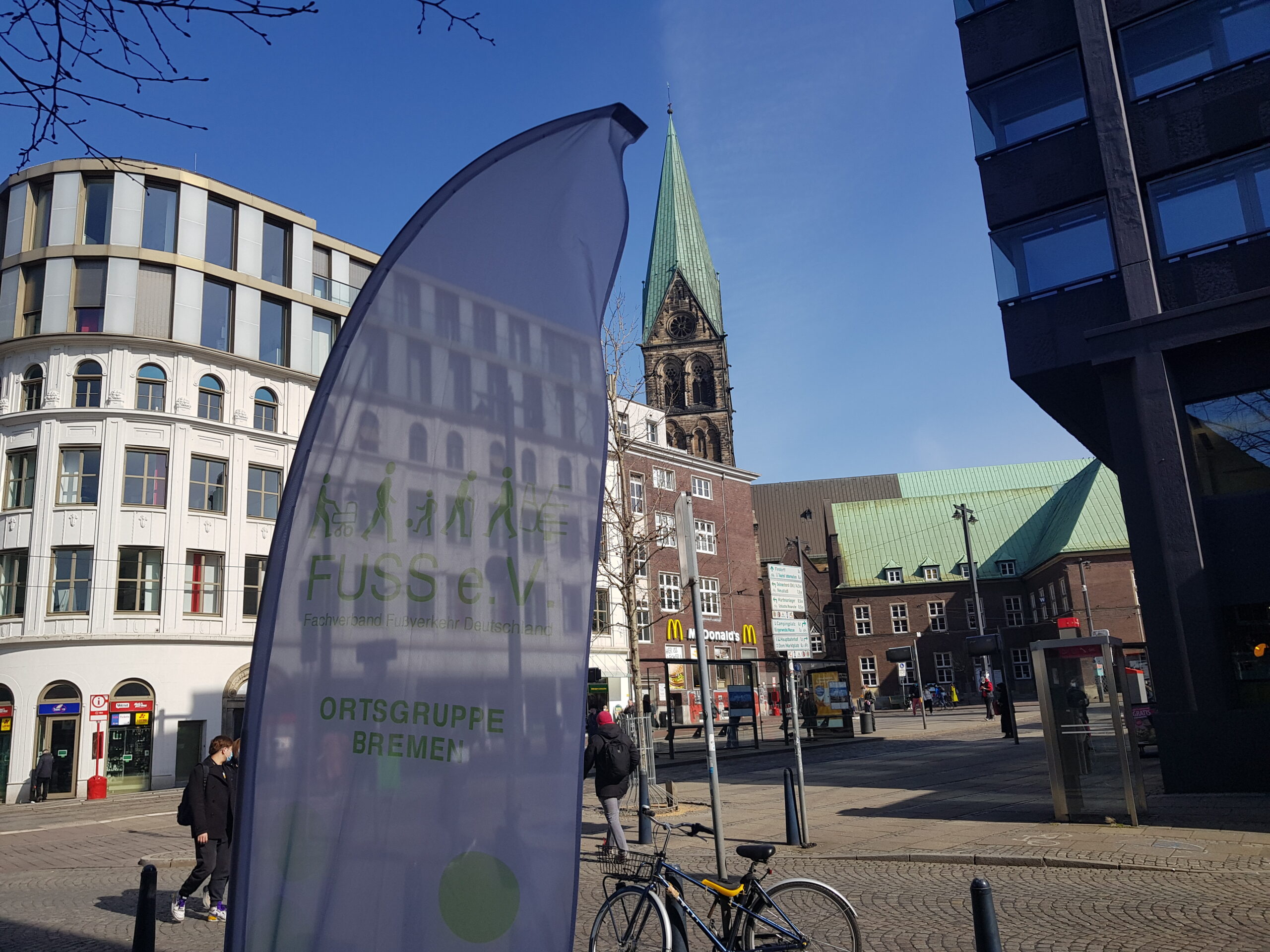 Haltestelle Domsheide in Bremen. Im Vordergrund das Banner des FUSS e.V. Bremen.Der FUSS e.V. - Ortsgruppe Bremen stellt seine Ziele und Schwerpunkten vor. Wir setzen uns für einen sicheren, gesunden und klimagerechten Fußverkehr ein