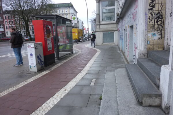 Ein neuer breiter Radweg mit beidseitiger Noppenmarkierung wird an Bushaltestelle vorbeigeführt. Der Gehweg ist zu schmal.