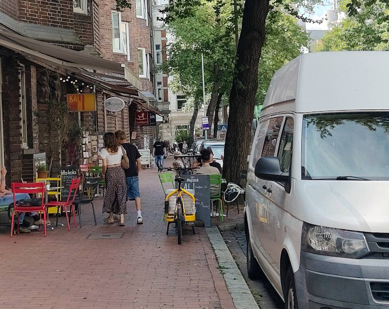 Wegen parkenden Autos, abgestellten Fahrrädern und Außengastronomie bleibt Fußgänger*innen oft nur wenig Platz.