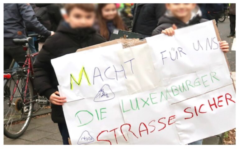 Kinder halten ein selbst gemaltes Plakat hoch mit dem Satz Macht für uns die Luxemburger Straße sicher; © Wolfgang Scheible