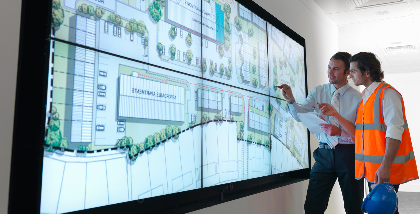 zwei Verkehrsplaner / Ingenieure stehen vor einem Stadtplan und diskutieren