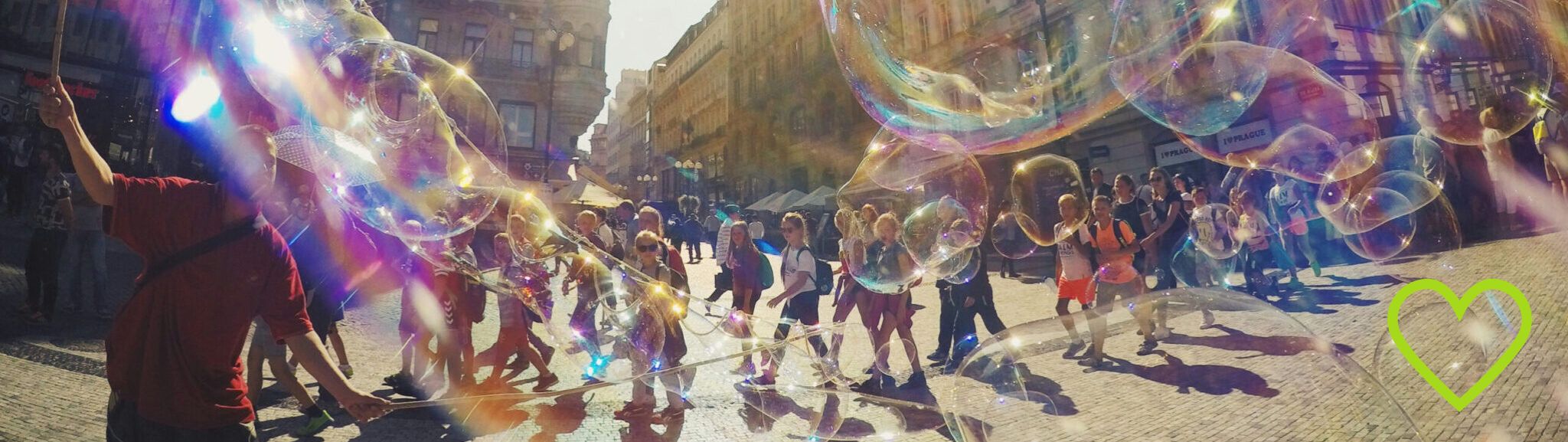 eine Gruppe Kinder läuft durch die Stadt, im Vordergund bunte Seifenblasen