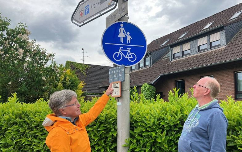 Ehepaar Ditzen vor einem Schild für den gemeinsamen Geh- und Radweg